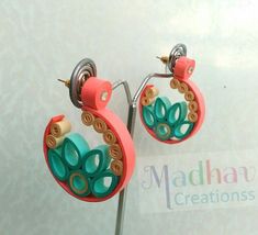 two pairs of colorful earrings hanging from a metal hook on a white background with the words madha creations written below it