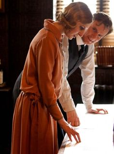 a man and woman standing next to each other in front of a table