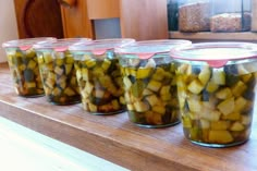 several jars filled with pickles sitting on top of a counter