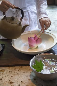 a person pouring water into a bowl with a teapot