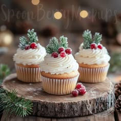 three cupcakes with white frosting and cranberries on a wooden board