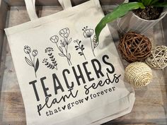 a teacher's plant seeds tote bag sitting on top of a wooden table