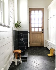 a black and white tiled bathroom with yellow rubber boots on the floor next to the shower