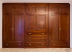 a large wooden closet with many drawers and doors on the wall, in a home