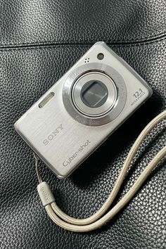 a silver camera sitting on top of a black leather surface