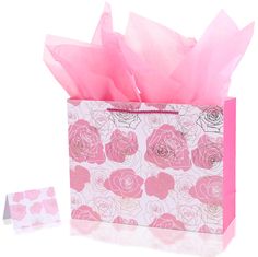 a pink tissue paper bag with roses on it and two small tissues in front of it