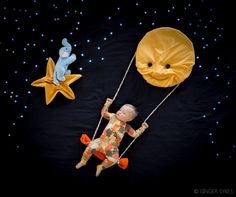 an overhead view of a baby doll on a swing next to two stars and a moon