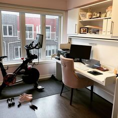 an office with a bike, desk and computer on the floor in front of a window