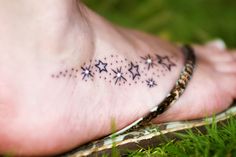 a small star tattoo on the foot of a person's foot with grass in the background