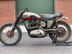 an old motorcycle is parked in front of a garage