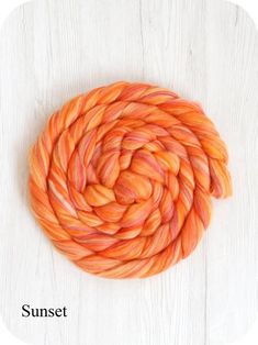 an orange and pink colored yarn is on a white wooden surface with a circular design