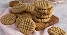 peanut butter cookies on a wooden cutting board with pink napkin and glass of milk in the background