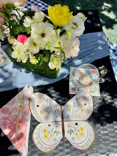 a table topped with plates and flowers on top of a checkered cloth