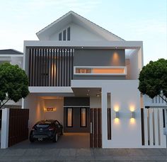 a car is parked in front of a modern house with lights on the windows and doors