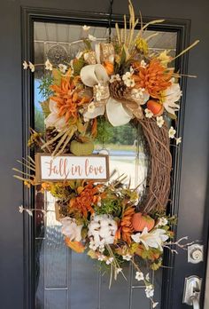 a wreath that has been decorated with flowers and leaves is hanging on the front door