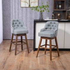 two gray chairs sitting next to each other on top of a hard wood floor in front of a bar