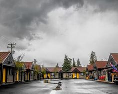 an empty street lined with small houses under a cloudy sky