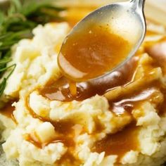 a spoon full of gravy on top of mashed potatoes