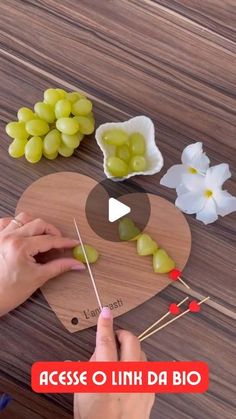 a person cutting up grapes on top of a wooden board next to flowers and scissors