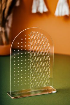 an acrylic display stand on top of a green table next to a potted plant