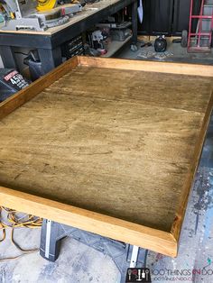 an unfinished bed frame in a garage with tools on the floor and workbench behind it