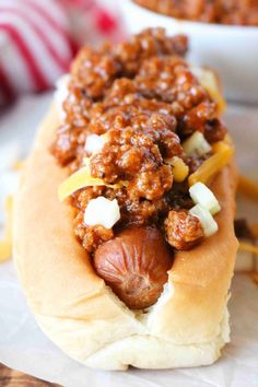 a chili dog on a bun with cheese and onions