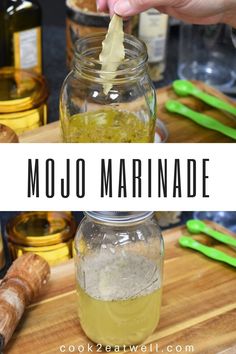 a hand is dipping something into a jar with liquid in it and the words mojo marinade above it