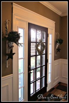 the front door is decorated for christmas with wreaths and greenery hanging on it