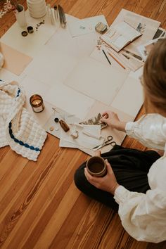 a woman sitting on the floor working on crafts