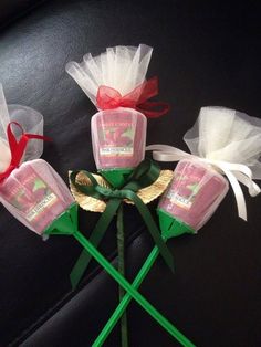 four roses are wrapped in organ bags and tied with green ribbon on a black surface