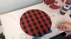 a person is painting a red and black plaid circle