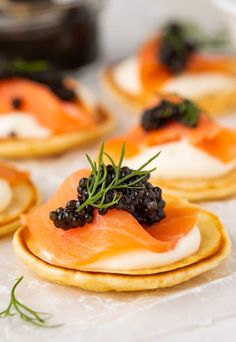 small crackers with various toppings on them sitting on a white tablecloth covered surface