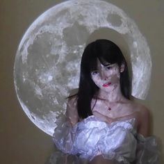 a woman in white dress standing next to the moon with her hands on her hips