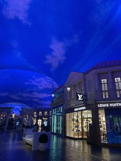 the sky is very blue and there are clouds in the sky over shops at night