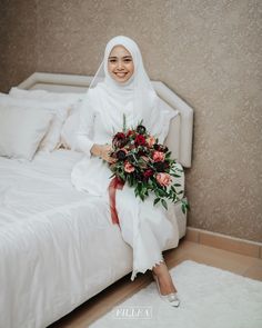 a woman sitting on top of a bed holding a bouquet