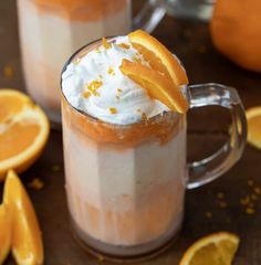 two mugs filled with whipped cream and orange slices