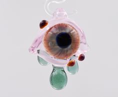 an eyeball hanging from a string with glass beads on it's end and inside