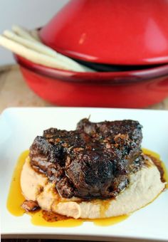 a plate with some food on it next to a red bowl and utensils