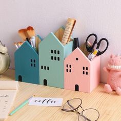 a wooden desk topped with lots of office supplies next to a pen and eyeglass holder