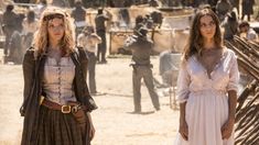 two women standing next to each other on a dirt field