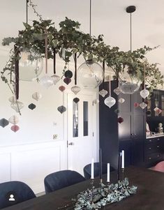 a dining room table with hanging plants on the wall and candles in front of it