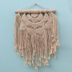 a macrame wall hanging on a blue wall