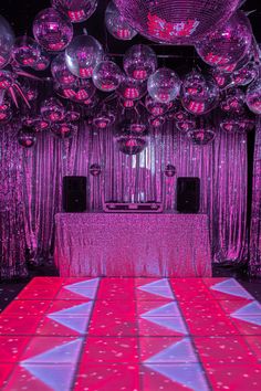 the dance floor is covered with pink and purple lights, while disco balls are hanging from the ceiling