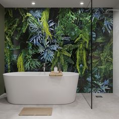 a bath tub sitting next to a wall covered in green leaves and plants on it