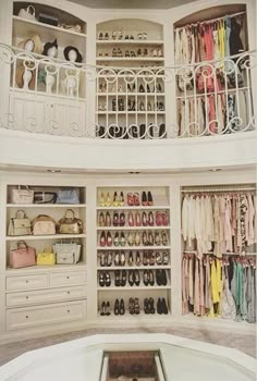 an organized closet with shoes, purses and handbags on the bottom shelf in front of a spiral staircase