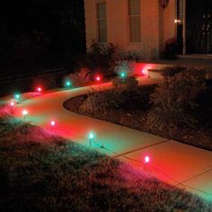 some green and red lights are on the ground in front of a house at night