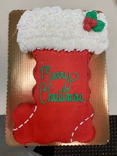 a decorated christmas stocking on top of a cake with white frosting and green writing