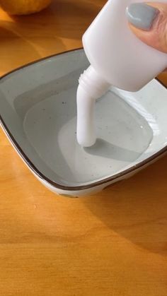 a person is pouring something into a bowl on a table with oranges in the background