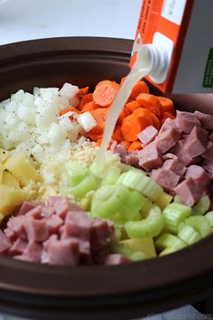 someone pouring milk into a bowl filled with chopped vegetables and ham, carrots, celery, onions