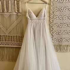 a white dress hanging on a wall next to a macrame woven wall hanging